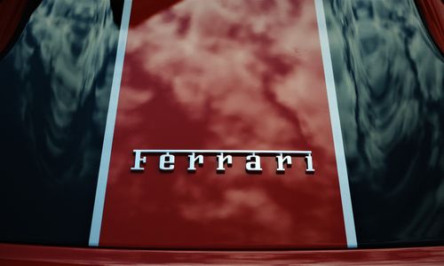 Free Close-up view of a vibrant red Ferrari hood with reflective surface and iconic logo. Stock Photo