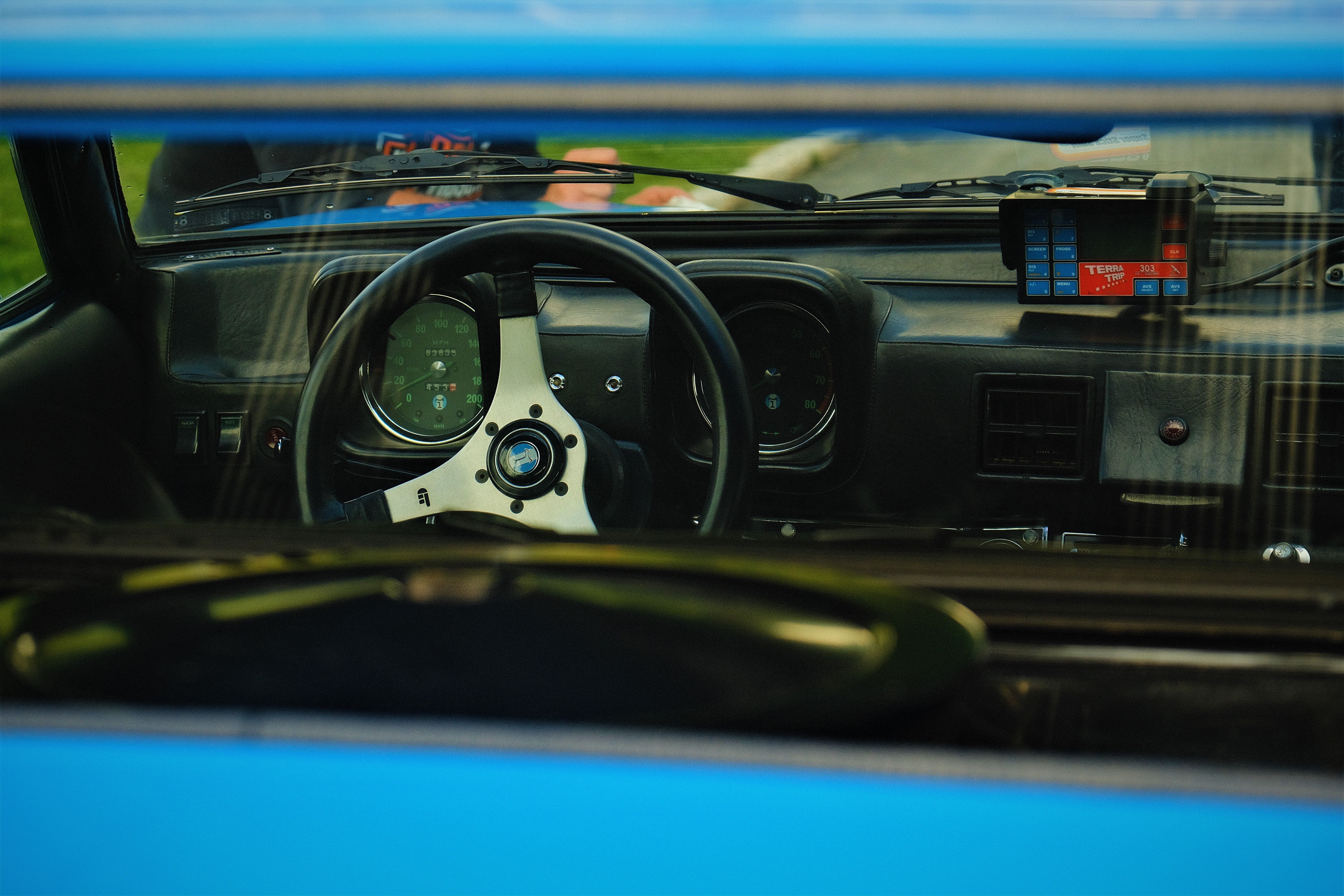 Interior shot of a classic car's steering wheel and dashboard, emphasizing vintage design.