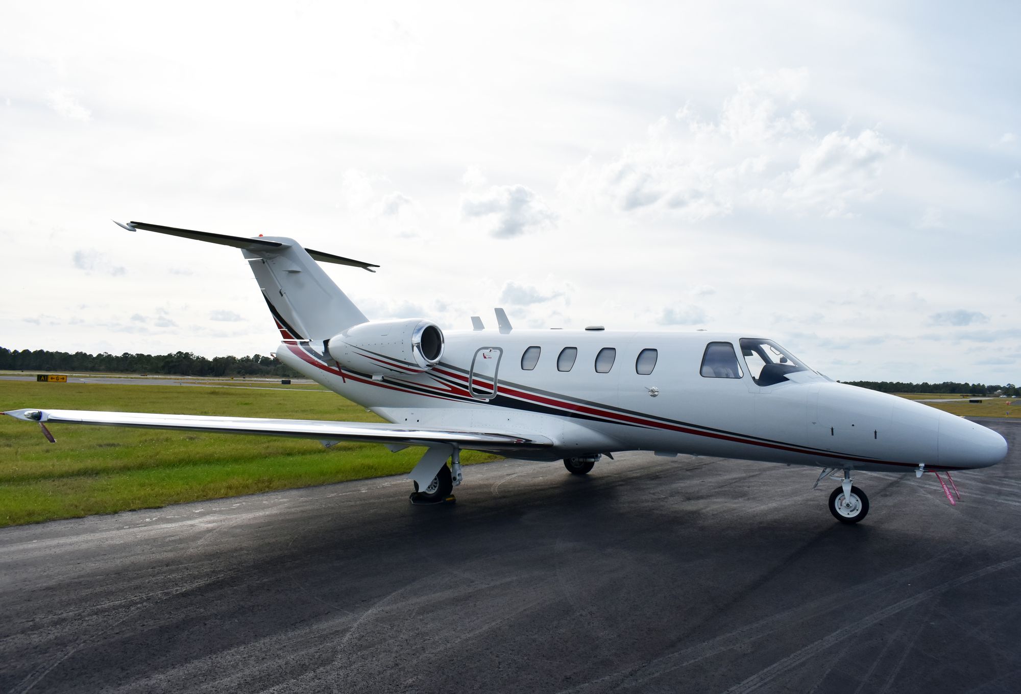 A light business jet parked on a damp runway, the smaller side of the light jet vs midsize jet decision