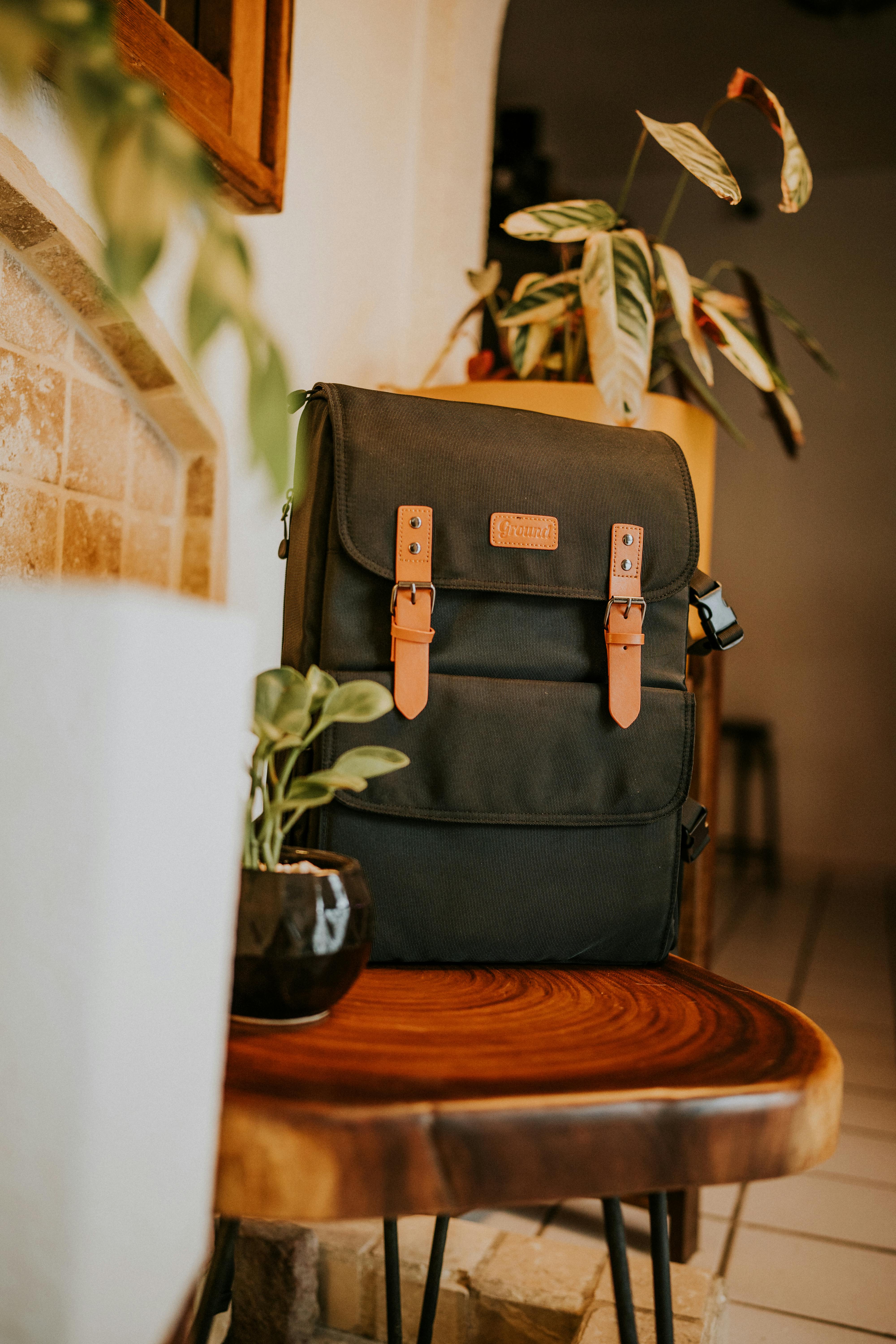 black backpack and potted plant on a wooden table