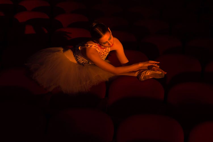 Woman In Ballet Dress Sitting On Red Chairs