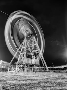 Stunning black and white long exposure of a Ferris wheel spinning at night.