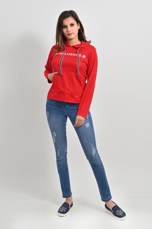Free Stylish woman posing in a red hoodie and jeans in a studio setting. Stock Photo