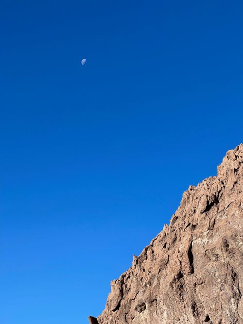 Free Eroded rock formations in Atacama Desert under clear blue sky with visible moon. Stock Photo