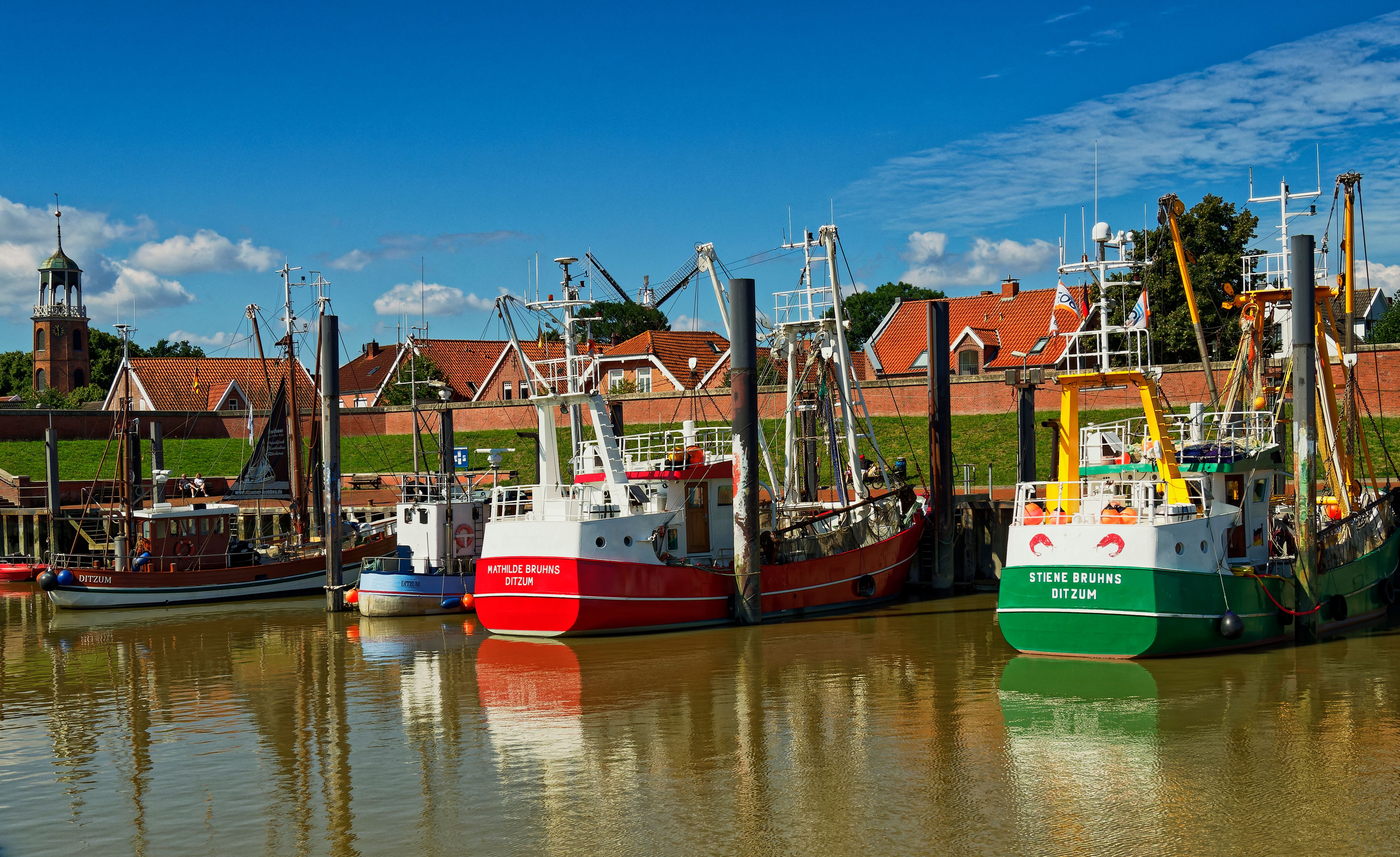 Scenic view of colorful fishing boats moored at Ditzum Harbor on a sunny day in Germany.