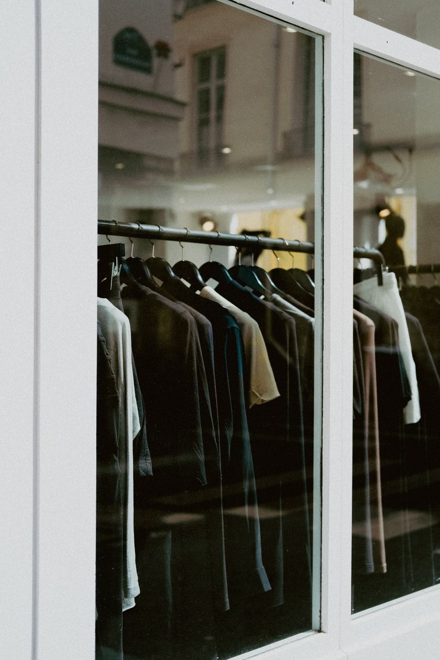 Close-up of clothes hanging on racks in a boutique window display, ideal for fashion backdrops.