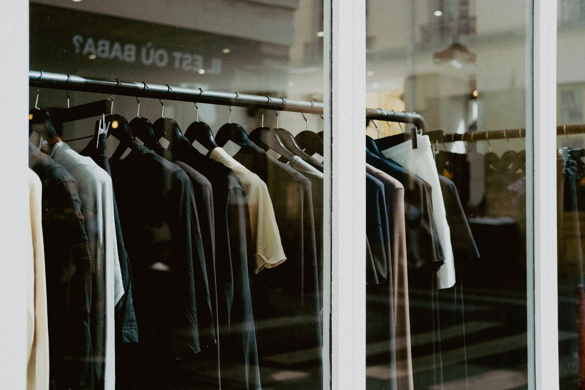 Close-up of clothing on hangers inside a fashion store window.