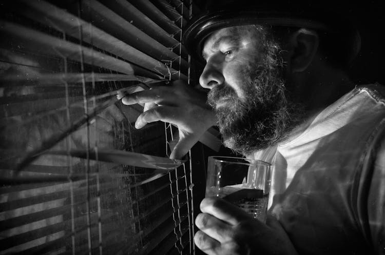 Man Looking Through Window Blinds 