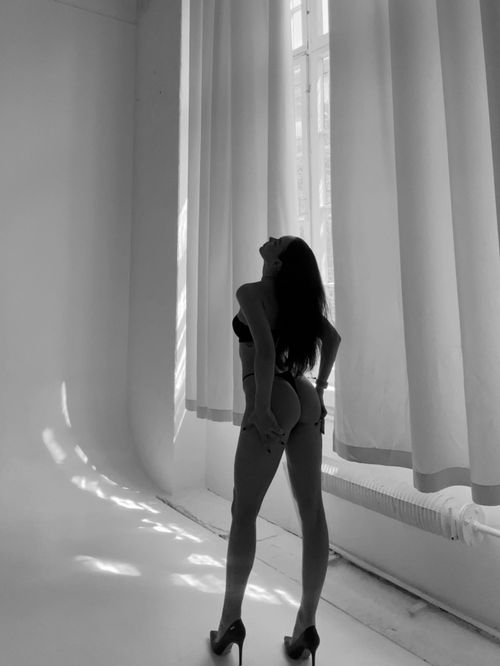 Free Black and white photo of a woman posing in lingerie by a large window. Stock Photo