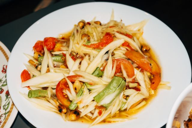 Close-up of a traditional Thai som tam papaya salad with fresh vegetables.