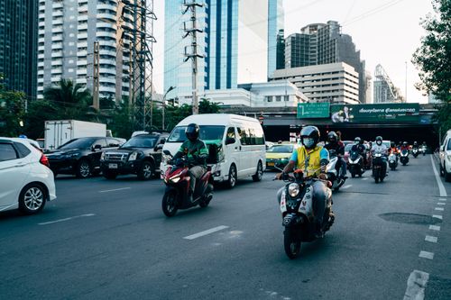 Free Busy city street with motorcyclists and vehicles. Urban commuting in action. Stock Photo