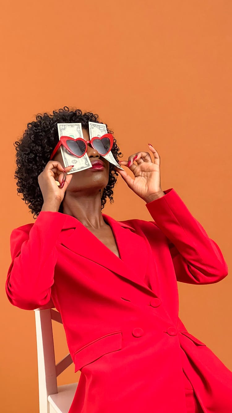 Woman Holding Dollars Behind Sunglasses