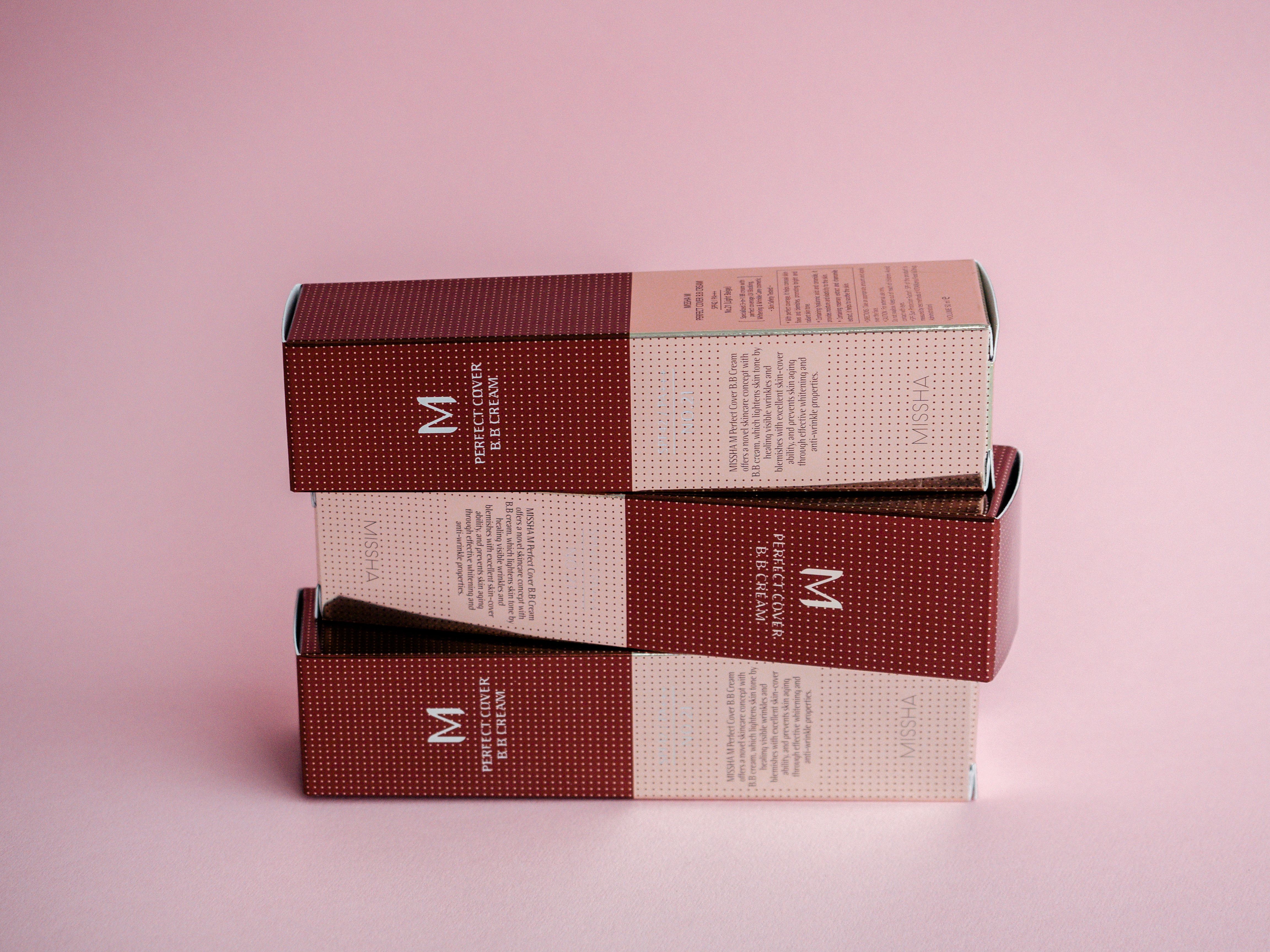 Sophisticated display of luxury cosmetic boxes against a pastel pink backdrop.