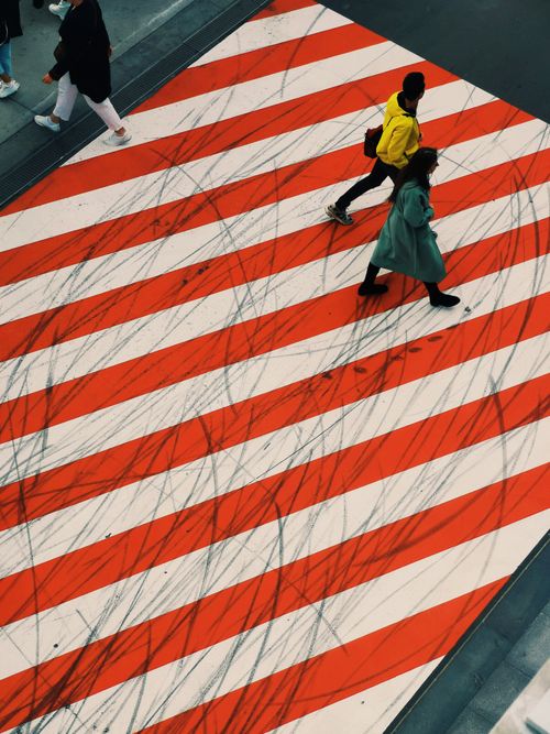 Free Two people crossing a uniquely striped urban street. Top-down view. Stock Photo