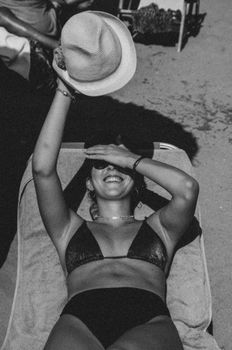 Black and white photo of a smiling woman lounging in a bikini at Kavala beach.