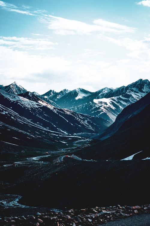 Free Breathtaking view of snow-capped mountain range and valley under a cloudy sky. Stock Photo