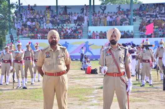 Uniformed officers stand in formation during a traditional military parade with spectators.
