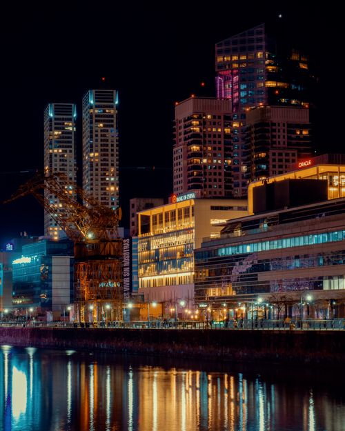 Free Vibrant cityscape reflecting in water, showcasing modern architecture and night lights. Stock Photo