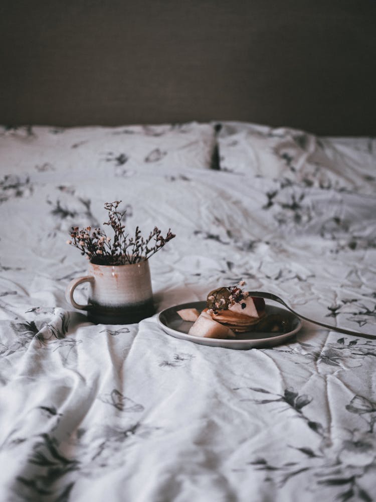 Slice Of Cake And Flowers In A Mug On A Bed 