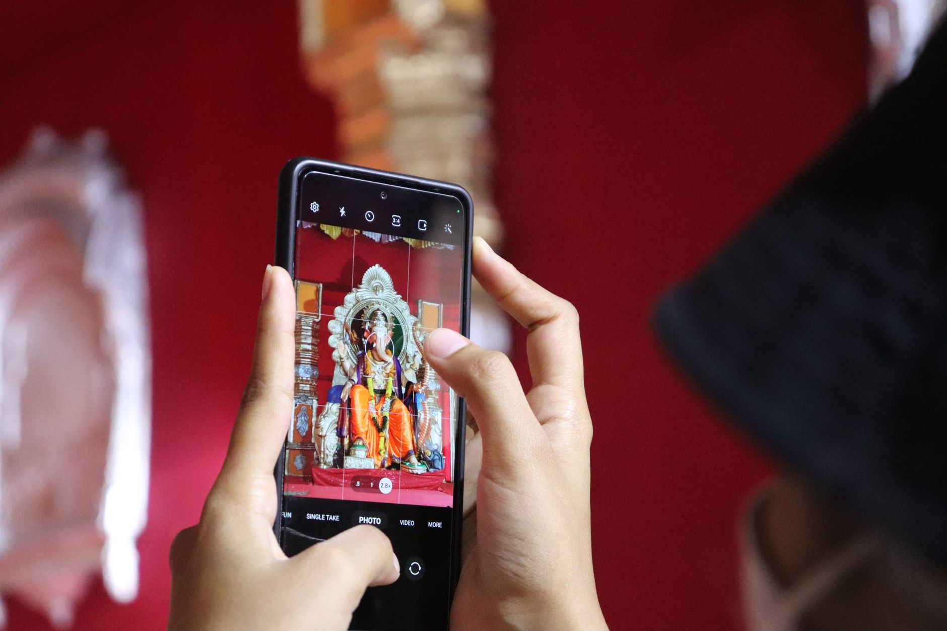 स्मार्टफोन पर विलो टीवी कार्यक्रम देखते दर्शक, पास में क्रिकेट आँकड़ों वाला लैपटॉप खुला है