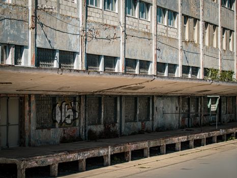 Captivating image of an abandoned building with a weathered, graffiti-covered facade in the sunlight.