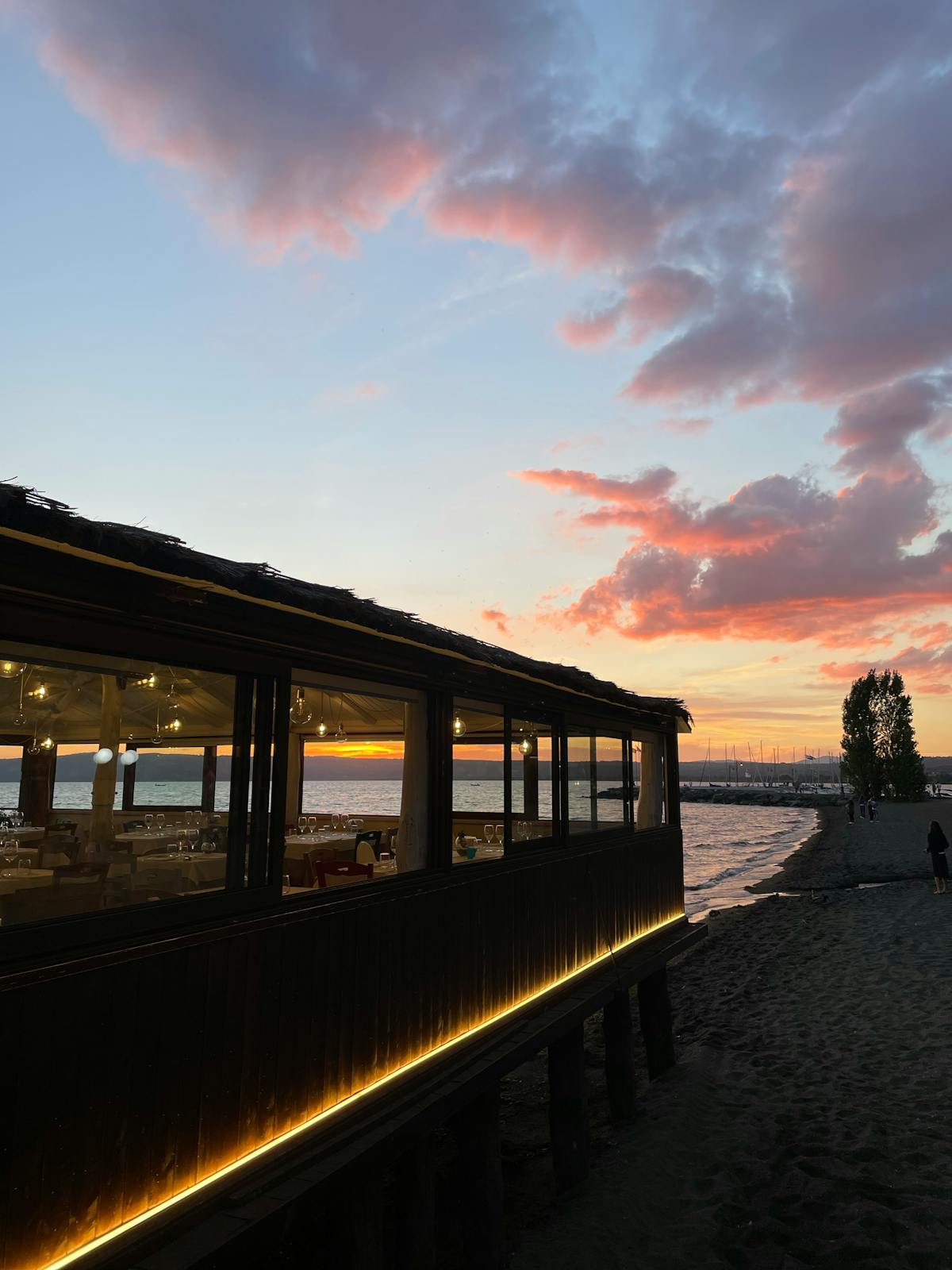 Tavoli da ristorante all'aperto sulla spiaggia al tramonto con ombrelloni