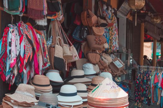 Vibrant market stall displaying hats, bags, and scarves in an outdoor setting.