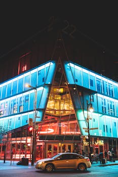 Modern architecture lit up at night in vibrant colors on a busy Montréal street.