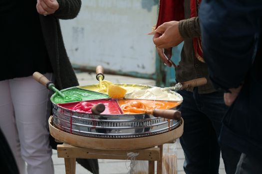 Traditional Turkish street food vendor preparing colorful Macun sweets for customers outdoors.