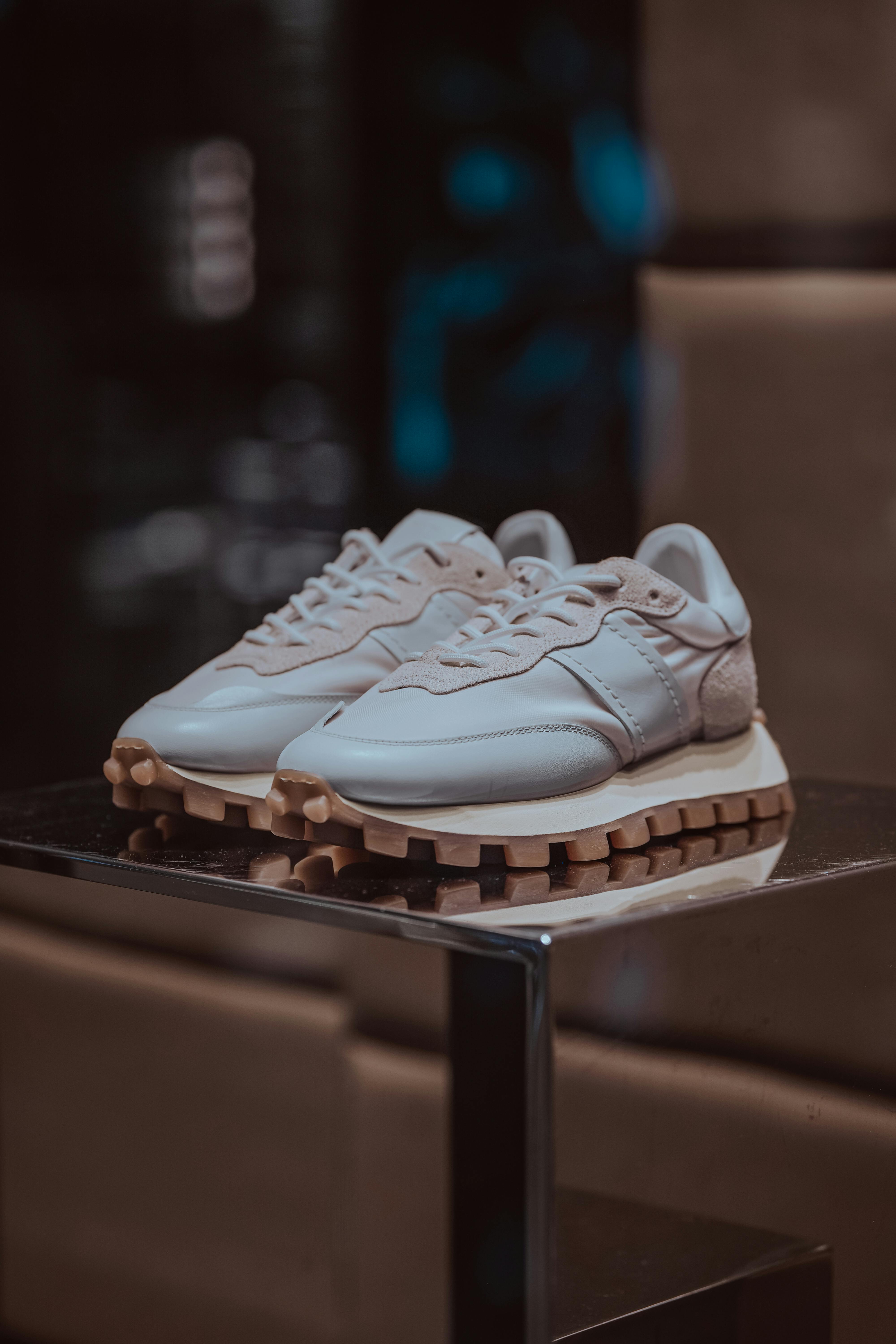 Elegant white sneakers displayed on a reflective surface, perfect for fashion-forward looks.