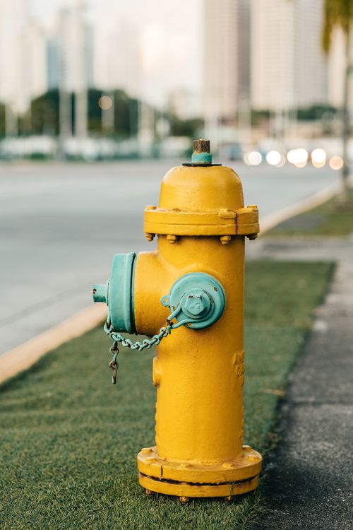 Free A bright yellow fire hydrant standing prominently on a city sidewalk beside the street. Stock Photo
