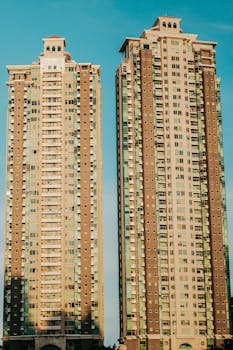 Two high-rise buildings stand tall against a clear blue sky, showcasing modern architecture.