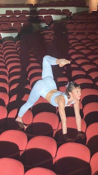 Woman performing yoga pose in empty theater, showcasing balance and flexibility.