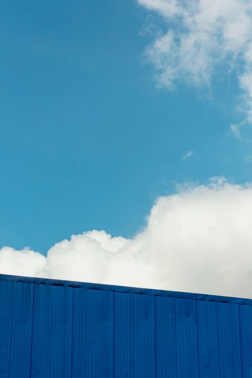 Free Minimalist photo featuring a vibrant blue wall against a clear cloudy sky. Stock Photo