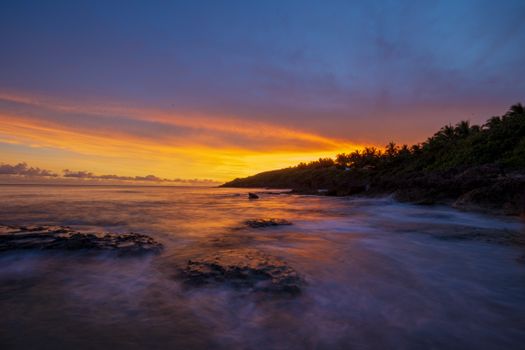 Stunning sunset over a rocky coastline with vibrant sky colors.