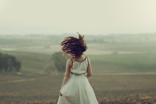 Back View of a Woman Running Through a Foggy Field 