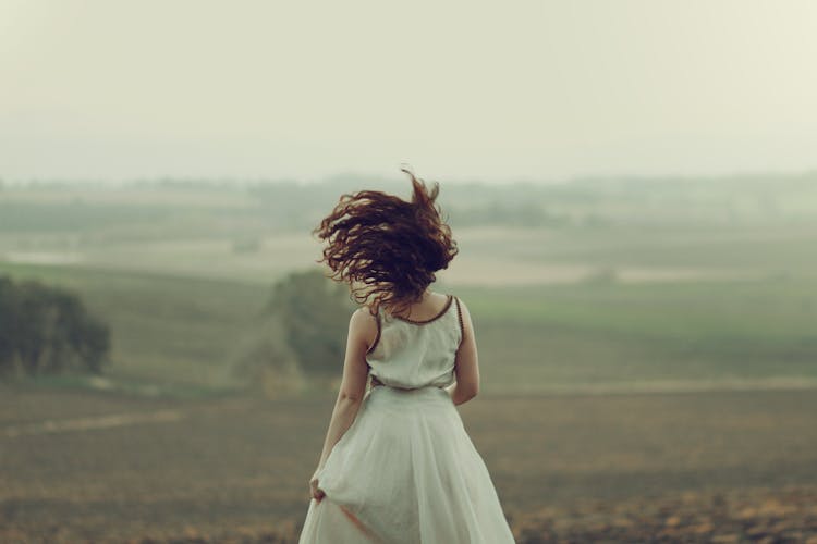 Back View Of A Woman Running Through A Foggy Field 