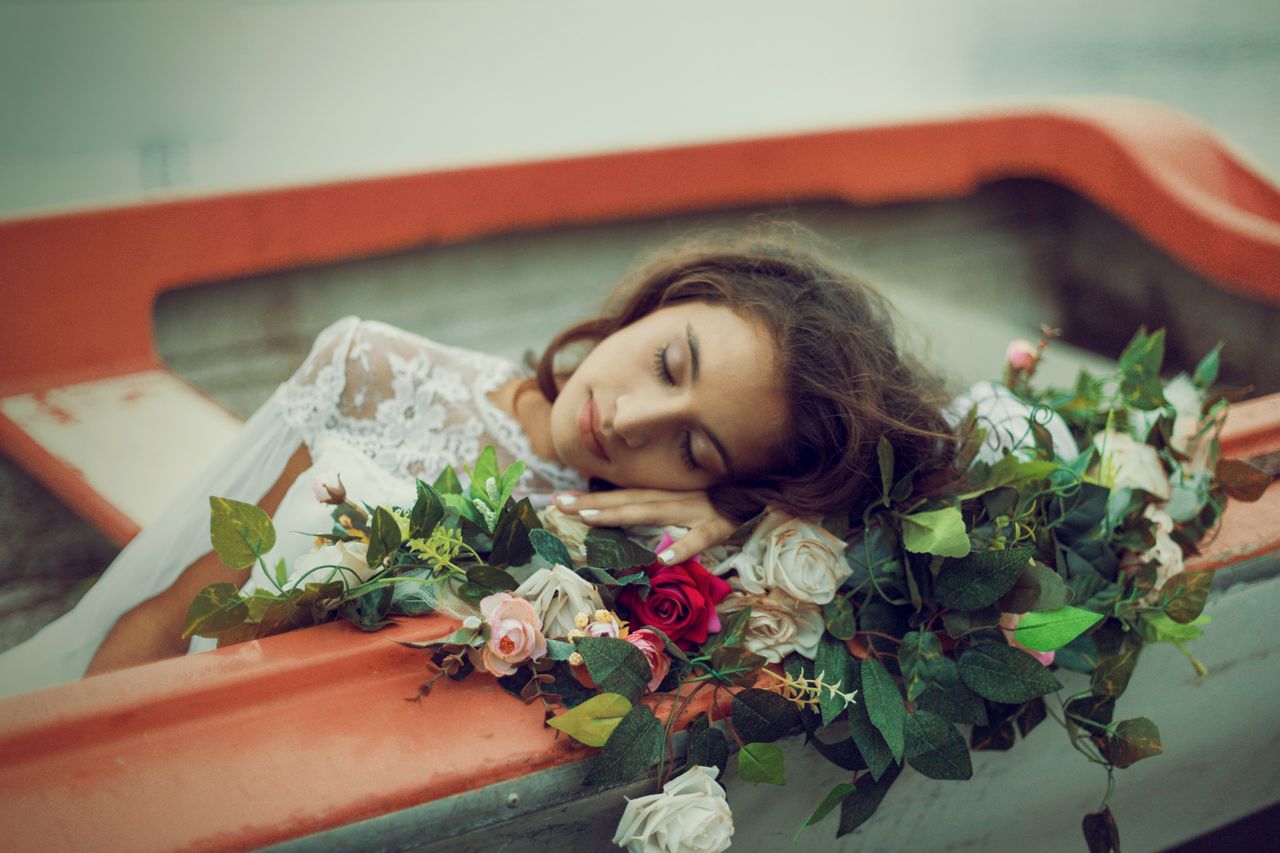 graceful woman in white lace dress rests with eyes closed among vibran