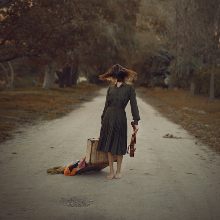 Woman Carrying Suitcase And Instrument On Ground Road