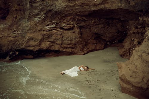 Woman in Dress Lying Down on Shore