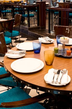 A well-arranged table setting in a restaurant featuring colorful glassware and neatly arranged cutlery.