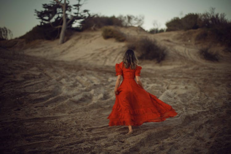 A Woman In Red Dress Walking On Sand