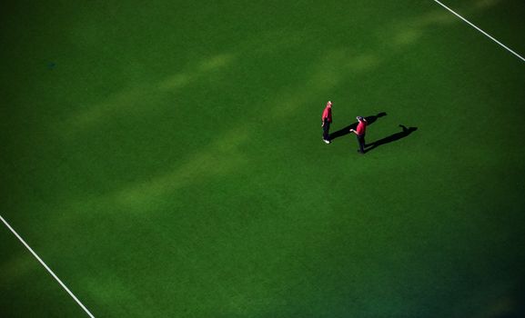 Overhead shot of two individuals standing on a green sports field, providing ample copy space.
