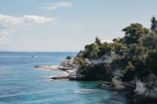 Free Discover the serene rocky coastline with turquoise waters and lush greenery in Gaios, Greece. Stock Photo