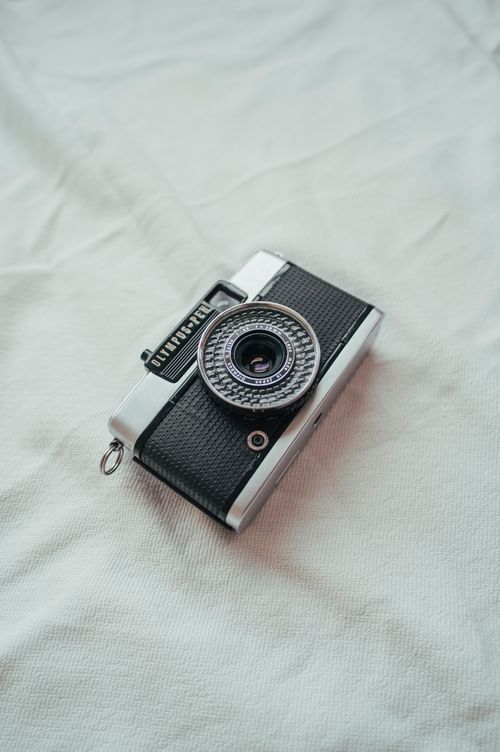 Free Classic Olympus Pen analog camera on a soft fabric background, perfect for nostalgic themes. Stock Photo