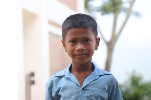 Free Close-up portrait of a young boy wearing a blue shirt outdoors with blurred background. Stock Photo
