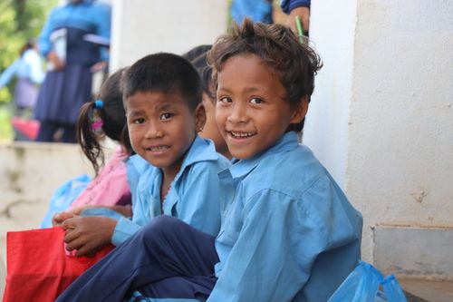Free Happy children in blue uniforms sitting outdoors, enjoying school life. Stock Photo