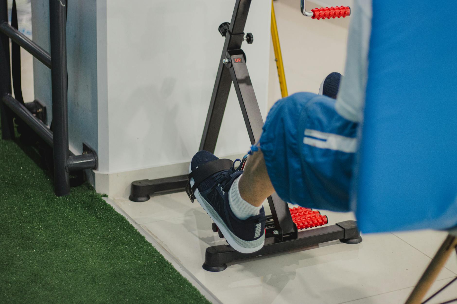 Close-up of a man working out on a stationary bike indoors, focusing on fitness and health.