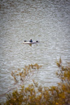 A lone kayaker enjoys a tranquil paddle on a calm lake in La Rioja, Argentina.