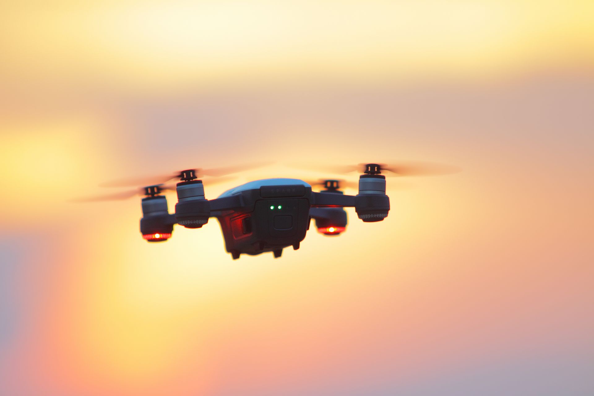 Aerial drone photography capturing a drone flying in a vibrant sunset sky.